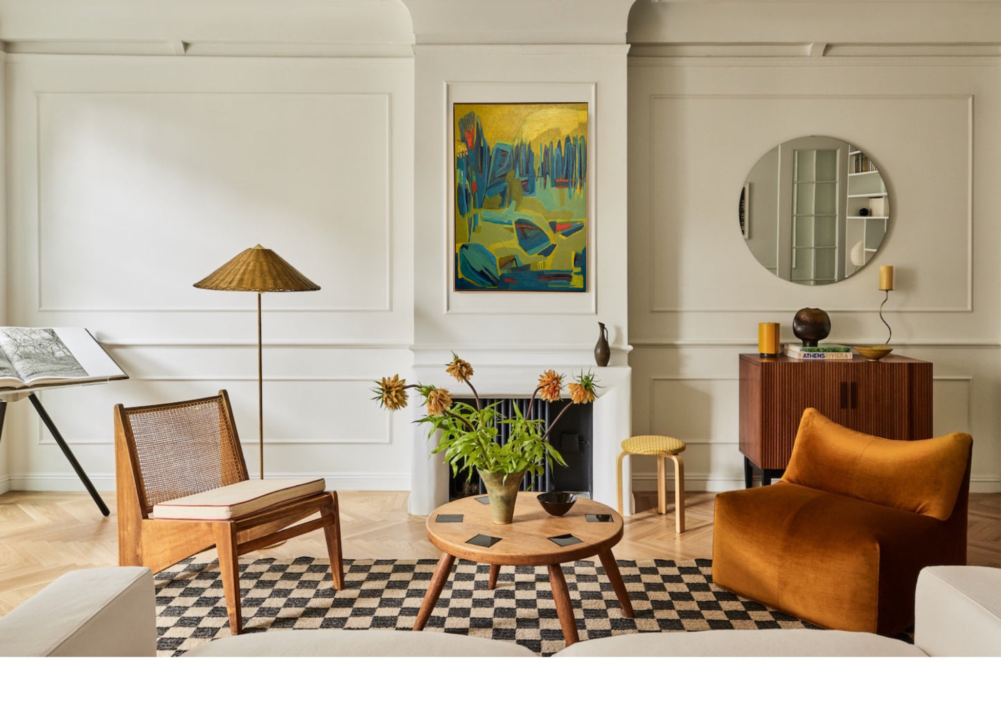 Contemporary living room with modern furniture, checkered rug, and original green and and gold vertical nature inspired oil painting on wall.