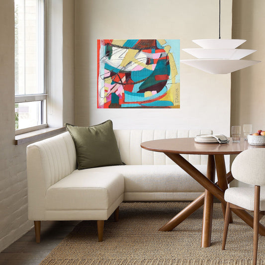 Red, aqua and yellow abstract painting on canvas created by artist danielle nelisse installed on white wall in modern luxury breakfast nook above designer white sofa in front of brown wood table and upholstered white chair