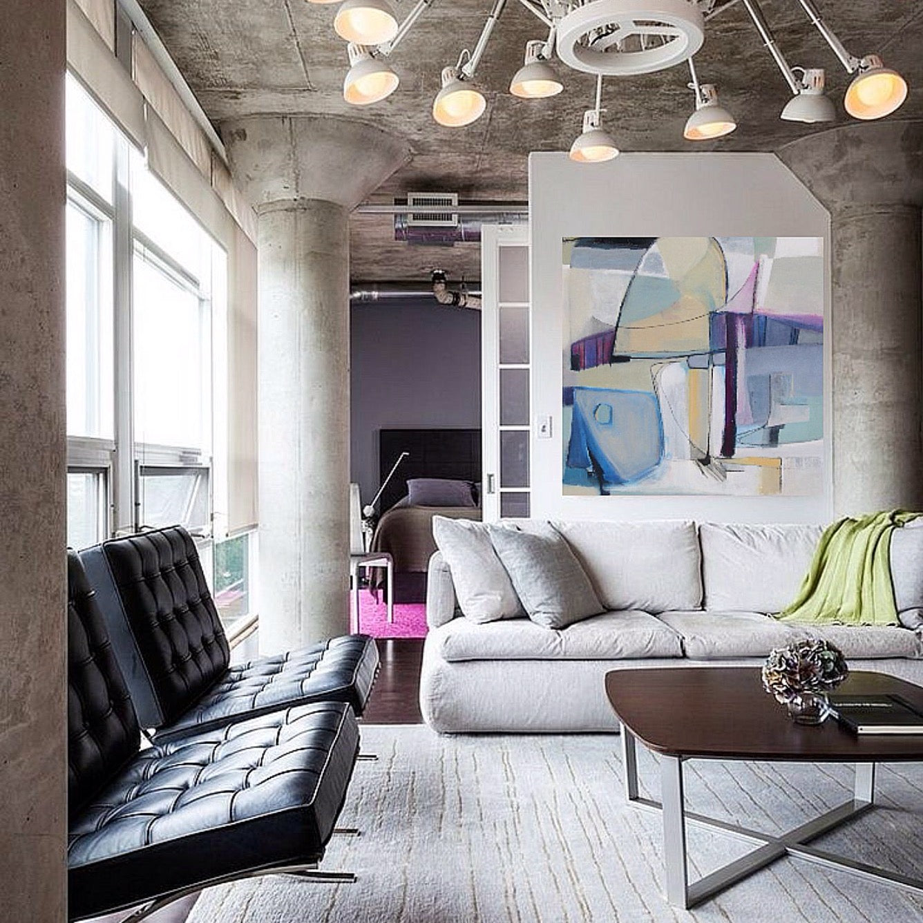 soft white pale green light blue abstract shapes on oil painting is shown as focal point in living room with cement textured ceiling and black leather couch and soft white modern couch in luxury new york city style studio setting