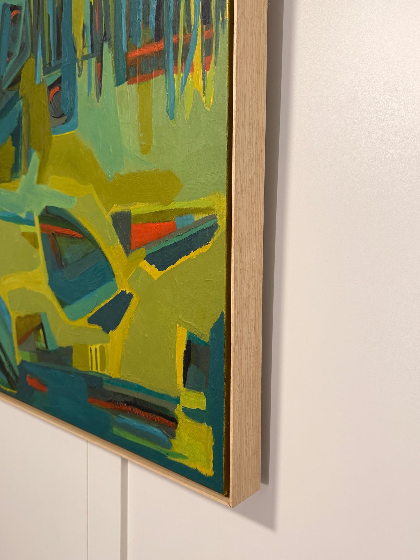 Abstract nature oil painting with green and blue tones on a white wall.