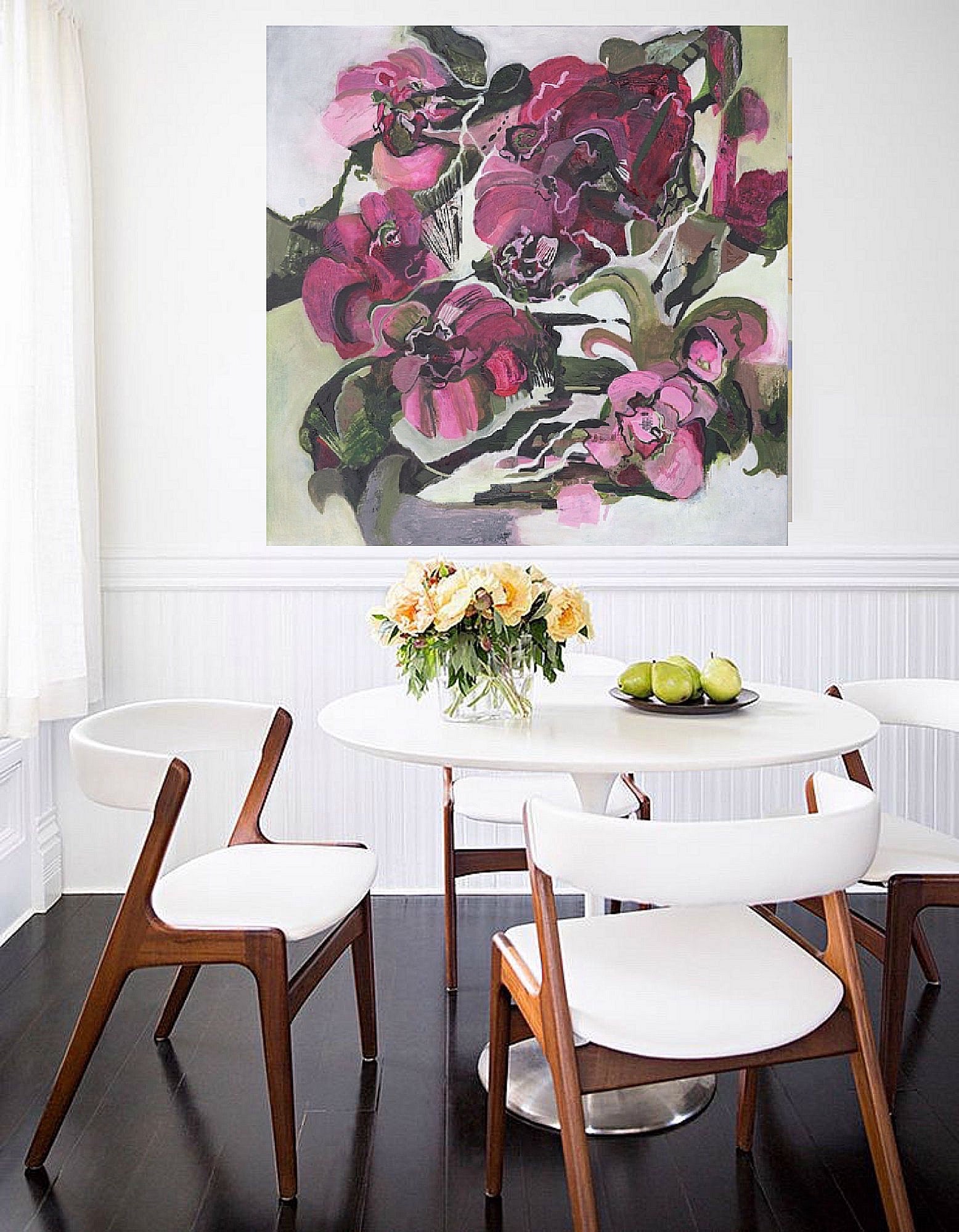 A floral abstract oil painting featuring magenta colors displayed above a dining table with white chairs in a room with dark wood flooring and white walls.